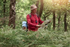 L'immagine dell'uomo del viaggiatore che cerca la giusta direzione sulla mappa, gradisce viaggiare lungo la natura Turista anzian fotografia stock L'immagine dell'uomo del viaggiatore che cerca la giusta direzione sulla mappa, gradisce viaggiare lungo la natura Turista anzian fotografia stock
