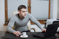 L'indépendant d'employé de bureau s'assied au bureau et à travailler à l'ordinateur portable pendant la pause-café au bureau images stock L'indépendant d'employé de bureau s'assied au bureau et à travailler à l'ordinateur portable pendant la pause-café au bureau images stock