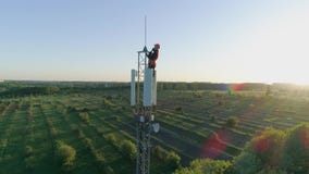 L'ingegnere con l'aggeggio ha collegato una comunicazione su mezzi mobili sulla torre radiofonica della telecomunicazione su fond stock footage L'ingegnere con l'aggeggio ha collegato una comunicazione su mezzi mobili sulla torre radiofonica della telecomunicazione su fond stock footage