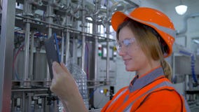 L'ingegnere femminile sul lavoro, giovane donna del tecnico della fabbrica nel casco usa la compressa del computer e la fabbricaz archivi video L'ingegnere femminile sul lavoro, giovane donna del tecnico della fabbrica nel casco usa la compressa del computer e la fabbricaz archivi video
