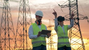 L'ingegnere in vetri di VR lavora al cantiere, mentre un elettricista scrive su una compressa L'ingegnere in vetri di VR lavora al cantiere, mentre un elettricista scrive su una compressa