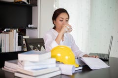 L'ingénieur asiatique de femmes sont eau potable et travail au bureau photo stock L'ingénieur asiatique de femmes sont eau potable et travail au bureau photo stock