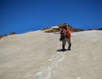 L'uomo adulto con lo zaino scala una montagna nevosa fotografia stock L'uomo adulto con lo zaino scala una montagna nevosa fotografia stock