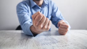L'uomo d'affari colpisce la tavola con i suoi pugni Concetto di rabbia fotografia stock L'uomo d'affari colpisce la tavola con i suoi pugni Concetto di rabbia fotografia stock