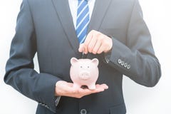 L'uomo mette le monete nel concetto di risparmio della banca- di porcellino immagine stock L'uomo mette le monete nel concetto di risparmio della banca- di porcellino immagine stock