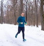 L'uomo negli sport blu indossa il funzionamento nella foresta fotografia stock L'uomo negli sport blu indossa il funzionamento nella foresta fotografia stock