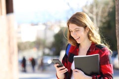 L'étudiant heureux utilise le téléphone intelligent dans la rue photo stock L'étudiant heureux utilise le téléphone intelligent dans la rue photo stock