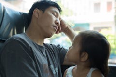 La bambina esamina il suo papà stanco mentre sta dormendo sul bus fotografia stock libera da diritti La bambina esamina il suo papà stanco mentre sta dormendo sul bus fotografia stock libera da diritti
