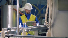 La banda transportadora con las pequeñas botellas plásticas está siendo observada por un especialista almacen de metraje de vídeo La banda transportadora con las pequeñas botellas plásticas está siendo observada por un especialista almacen de metraje de vídeo