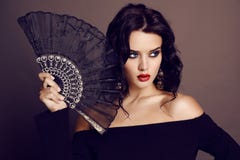 La bella donna sensuale con capelli scuri che tengono il pizzo nero smazza a disposizione Fotografia Stock La bella donna sensuale con capelli scuri che tengono il pizzo nero smazza a disposizione Fotografia Stock
