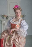 La bella donna sorridente nel rosa medievale della tenuta del vestito è aumentato immagine stock libera da diritti La bella donna sorridente nel rosa medievale della tenuta del vestito è aumentato immagine stock libera da diritti