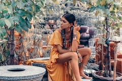 La bella giovane donna alla moda con compone ed accessori alla moda di boho che posano sul fondo tropicale naturale fotografie stock La bella giovane donna alla moda con compone ed accessori alla moda di boho che posano sul fondo tropicale naturale fotografie stock