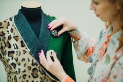 La bella giovane donna cuce il cappotto del progettista Cappotto e verde della stampa del leopardo immagine stock La bella giovane donna cuce il cappotto del progettista Cappotto e verde della stampa del leopardo immagine stock