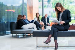 La belle femme attirante d'affaires utilise le comprimé tandis que sa Co photographie stock libre de droits La belle femme attirante d'affaires utilise le comprimé tandis que sa Co photographie stock libre de droits