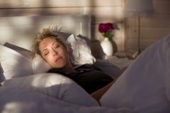 La belle femme blonde dort dans le lit, dans la maison en bois photographie stock La belle femme blonde dort dans le lit, dans la maison en bois photographie stock