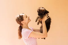 La belle femme dans un T-shirt rayé sourit et tient un petit chiot image stock La belle femme dans un T-shirt rayé sourit et tient un petit chiot image stock