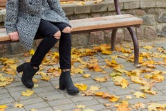 La belle fille douce avec les grands yeux tristes dans le manteau se reposant sur le banc en automne parmi le jaune tombé laisse Photo stock La belle fille douce avec les grands yeux tristes dans le manteau se reposant sur le banc en automne parmi le jaune tombé laisse Photo stock