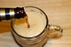 La birra nera sta versando nella tazza di vetro immagini stock La birra nera sta versando nella tazza di vetro immagini stock