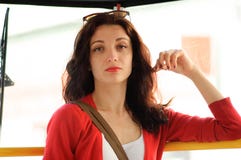 La brune mignonne conduit dans un tram Veste rouge, portrait en gros plan images stock La brune mignonne conduit dans un tram Veste rouge, portrait en gros plan images stock