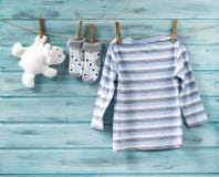 La camicia del neonato, i calzini ed il giocattolo bianco riguardano una corda da bucato immagine stock libera da diritti La camicia del neonato, i calzini ed il giocattolo bianco riguardano una corda da bucato immagine stock libera da diritti