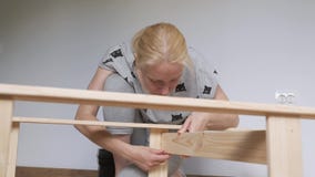 La casalinga della donna che si siede nella stanza sul pavimento, raccoglie lo scaffale di legno, comprato nel deposito Montaggio video d archivio La casalinga della donna che si siede nella stanza sul pavimento, raccoglie lo scaffale di legno, comprato nel deposito Montaggio video d archivio