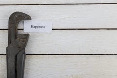 La chiave stringitubo comprime pezzo di carta con una felicità dell'iscrizione Immagine tonificata immagini stock La chiave stringitubo comprime pezzo di carta con una felicità dell'iscrizione Immagine tonificata immagini stock