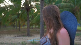 La chica joven en sombrero y vidrios azules va contra el fondo de las palmas de coco tropicales Ciérrese encima de tiro Cámara le metrajes La chica joven en sombrero y vidrios azules va contra el fondo de las palmas de coco tropicales Ciérrese encima de tiro Cámara le metrajes