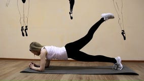 La chica joven hermosa en ropa de deportes hace ejercicios en una mentira de la extensión La chica joven hermosa en ropa de deportes hace ejercicios en una mentira de la extensión