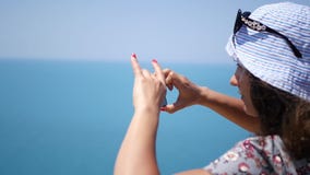 La chica joven hermosa en un sombrero tira un panorama del mar en el teléfono HD, 1920x1080 Cámara lenta almacen de metraje de vídeo La chica joven hermosa en un sombrero tira un panorama del mar en el teléfono HD, 1920x1080 Cámara lenta almacen de metraje de vídeo