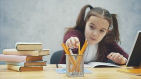 La colegiala inteligente, atenta realiza la preparación mientras que se sienta en la tabla Durante esta escritura, el lápiz toma metrajes La colegiala inteligente, atenta realiza la preparación mientras que se sienta en la tabla Durante esta escritura, el lápiz toma metrajes