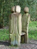 La colocación talló las figuras que rodeaban el banco en paseo del arbolado imagen de archivo La colocación talló las figuras que rodeaban el banco en paseo del arbolado imagen de archivo