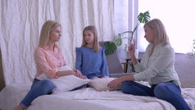 La communication gaie avec la maman, mère heureuse avec de belles filles parlent et ont l'amusement dans le lit de famille à la m La communication gaie avec la maman, mère heureuse avec de belles filles parlent et ont l'amusement dans le lit de famille à la m