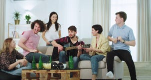 La compañía grande atractiva de étnico multi de los amigos tiene un buen rato junto en la sala de estar, algo del individuo en el almacen de video La compañía grande atractiva de étnico multi de los amigos tiene un buen rato junto en la sala de estar, algo del individuo en el almacen de video