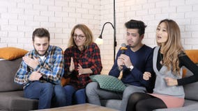 La compañía multinacional se sienta en el sofá y Karaoke del canto 50 fps La compañía multinacional se sienta en el sofá y Karaoke del canto 50 fps