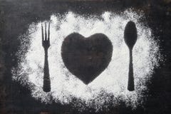 La cuillère, la fourchette et le plat au coeur forment, flour arrosé autour du photo libre de droits La cuillère, la fourchette et le plat au coeur forment, flour arrosé autour du photo libre de droits