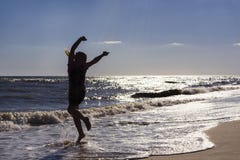 La danse de fille et rebondissement sur le bord de mer à l'arrière-plan du coucher du soleil image stock La danse de fille et rebondissement sur le bord de mer à l'arrière-plan du coucher du soleil image stock