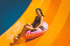 La donna castana che si diverte sull'acquascivolo in acqua parcheggia immagine stock libera da diritti La donna castana che si diverte sull'acquascivolo in acqua parcheggia immagine stock libera da diritti