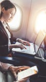 La donna di affari femminile sta lavorando al suo progetto facendo uso di un computer portatile mentre si sedeva in un aereo fotografia stock libera da diritti La donna di affari femminile sta lavorando al suo progetto facendo uso di un computer portatile mentre si sedeva in un aereo fotografia stock libera da diritti