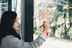 La donna di affari scrive sulle note adesive sulla parete di vetro nella riunione della r fotografia stock La donna di affari scrive sulle note adesive sulla parete di vetro nella riunione della r fotografia stock