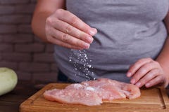 La donna di peso eccessivo passa l'aggiunta del sale ai petti di pollo crudi Dieti fotografia stock libera da diritti La donna di peso eccessivo passa l'aggiunta del sale ai petti di pollo crudi Dieti fotografia stock libera da diritti