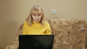La donna ha invecchiato con attenzione gli impianti ad un computer portatile a casa sullo strato Sta scrivendo sulla tastiera e s stock footage La donna ha invecchiato con attenzione gli impianti ad un computer portatile a casa sullo strato Sta scrivendo sulla tastiera e s stock footage