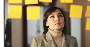 La donna invecchiata mezzo di affari sta attaccando i piccoli autoadesivi sul vetro nell'ufficio stock footage La donna invecchiata mezzo di affari sta attaccando i piccoli autoadesivi sul vetro nell'ufficio stock footage