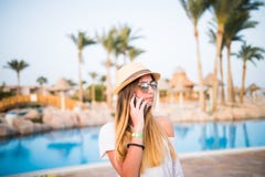 La donna parla sul telefono che si rilassa vicino alla piscina Vocazione di estate Immagine Stock Libera da Diritti La donna parla sul telefono che si rilassa vicino alla piscina Vocazione di estate Immagine Stock Libera da Diritti