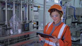 La donna potente ad industria pesante, ragazza sorridente dell'operaio nel casco utilizza la compressa digitale per i controlli e video d archivio La donna potente ad industria pesante, ragazza sorridente dell'operaio nel casco utilizza la compressa digitale per i controlli e video d archivio