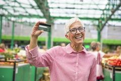 La donna senior tiene la carta di credito fotografia stock La donna senior tiene la carta di credito fotografia stock