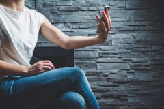 La donna sta sedendosi su una sedia, lei ha un telefono disteso, lei esamina il telefono cellulare fotografia stock La donna sta sedendosi su una sedia, lei ha un telefono disteso, lei esamina il telefono cellulare fotografia stock