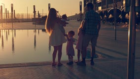 La familia feliz con tres niños que admiraban la puesta del sol reflejó en la superficie de la piscina imagen de archivo La familia feliz con tres niños que admiraban la puesta del sol reflejó en la superficie de la piscina imagen de archivo