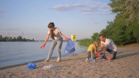 La famille des volontaires, du jeune père et de la mère avec la petite fille rassemble des ordures dans le sac de déchets sur la banque de vidéos La famille des volontaires, du jeune père et de la mère avec la petite fille rassemble des ordures dans le sac de déchets sur la banque de vidéos