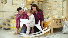 La famille heureuse avec la fille d'enfant en bas ?ge sur le cheval de basculage c?l?bre No clips vidéos La famille heureuse avec la fille d'enfant en bas ?ge sur le cheval de basculage c?l?bre No clips vidéos
