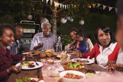 La famille multi de génération mangeant le dîner dans le jardin, se ferment photos libres de droits La famille multi de génération mangeant le dîner dans le jardin, se ferment photos libres de droits